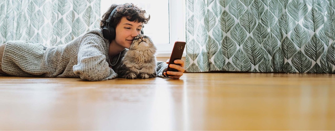 pessoa a ouvir música e a ver o telemóvel com o seu gato