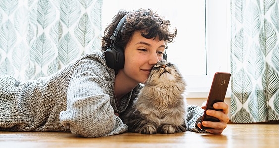 pessoa a ouvir música e a ver o telemóvel com o seu gato